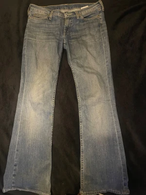 Levis 517 blå bootcut jeans - Säljer ett par klassiska Levis 517 jeans i ljusblå tvätt. De har bootcut passform med utsvängda ben och normal midja. Jeansen är tillverkade i slitstarkt bomullsdenim och har fem fickor samt bälteshällor. Perfekta för en avslappnad och cool look.