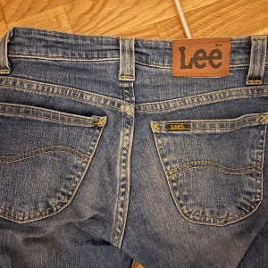 Blå bootcut jeans från Lee - Snygga blå jeans från Lee med klassisk bootcut passform och låg midja. Jeansen är så snygga men kommer tyvärr inte till användning längre och är fortfarande i topp skick jag är 158cm och dom passar bra i längden kan även passa nån som är 160cm elr längre