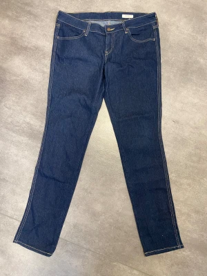 Mörkblå jeans från SQIN - Mörkblå jeansbyxor från Squin i storlek 31x32. Klassisk femficksmodell med kontrastsömmar och raka ben. Perfekta för dig som gillar en enkel och stilren look. .