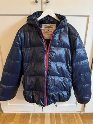 Marinblå pufferjacka från Replay XL - Säljer en marinblå pufferjacka från Replay i storlek XL. Materialet är glansigt. Fint skicka och sparsamt använd!