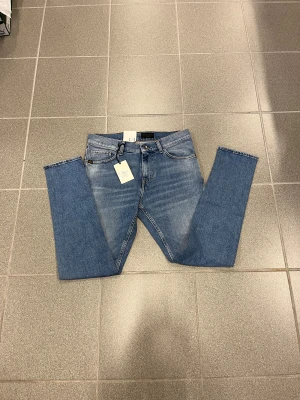 Slim fit jeans från Tiger of Sweden w29 L30 - Snygga blå jeans från Tiger of Sweden i slim fit-modell. Klassisk femficksdesign, ljus tvätt med subtila slitningar och bruna detaljer vid linningen. Perfekt passform för dig som gillar smalare siluett och stilren look.