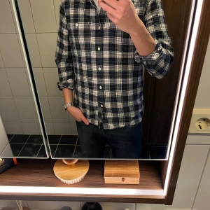 Rutig skjorta från Blueprint, marinblå/vit - Säljer en snygg rutig skjorta från Blueprint i marinblått och vitt. Skjortan har klassisk krage, långa ärmar och vita knappar framtill samt två bröstfickor. Regular fit för en avslappnad look. Perfekt till jeans och funkar året runt.