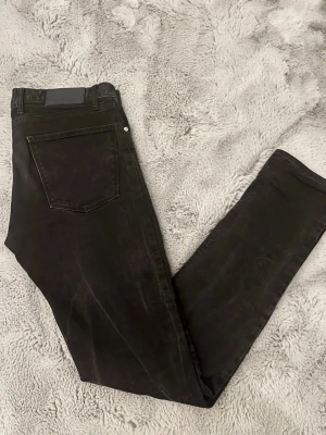 Slimfit Jeans J.Lindeberg - Svarta jeans från J.Lindeberg. Jeansen har en slim passform, tillverkade i stretchig bomull för skön komfort. Snyggt JL-logo på fickan och diskret tvättad look. Storlek 32w/34l. 