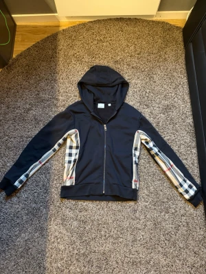 Svart-burberry hoodie - Säljer min svarta Burberry hoodie som är i bra skick. Den passar mig bra och jag är 16 år. Rekommenderas för personer runt 170 cm och väger 50-60 kg men den funkar även för någon som är upp till cirka 175 cm beroende på hur man vill att den ska sitta. En skön och snygg hoodie som jag inte använder längre. Skriv om du vill ha fler bilder eller undrar något.
