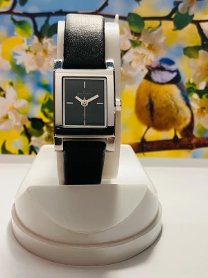 Snygg Svart Skagen klocka med läderarmband - Stilren klocka från Skagen med svart fyrkantig urtavla och matchande svart läderarmband. Boetten är i silverfärgad metall och har minimalistiska detaljer på urtavlan. Spännet är också i silver och har Skagen-loggan. Perfekt för dig som gillar klassisk och modern design.