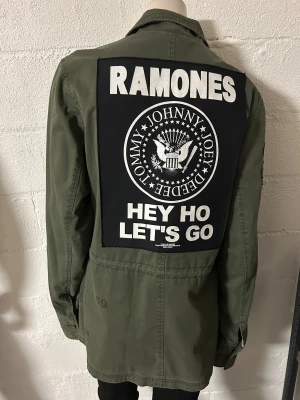 Jacka med Ramones patches på ryggen i storlek M. - Helt ny jacka med Ramones patches på ryggen. Material i bomull, även fodret är i bomull. Innerfickor.