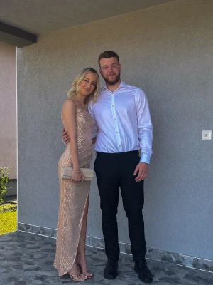 Rose glittrig långklänning - Säljer en rosafärgad långklänning med tunna axelband och glittriga paljetter över hela klänningen. Klänningen har en snygg draperad överdel och en hög slits på ena sidan. Perfekt för bal eller fest, ger en riktigt lyxig känsla. Endast använd 1 gång ( bröllop) 