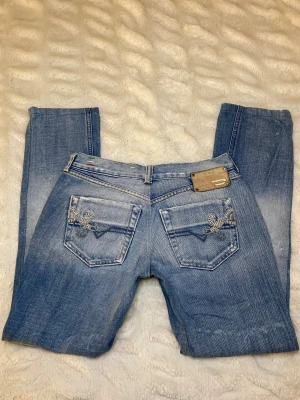 Ljusblå Diesel jeans - Ljusblå lågmidjade Diesel jeans med broderade detaljer. Strl W28 L34 (passar som S).