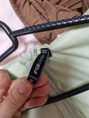 Ljusgrön kortklänning från FB Sister - Supersöt ljusgrön kortklänning från FB Sister med v-ringning, långärmade ärmar och volangkant nertill. Klänningen har ett diskret prickigt mönster, snörning framtill och en liten cut-out under bysten. Perfekt för vår och sommar!