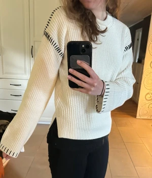 Vit stickad tröja med detaljer - Säljer en vit stickad tröja i storlek S. Tröjan har svarta dekorativa sömmar vid axlar och ärmslut. Ribbstickad med slits i sidan. Nypris 600❤️oanvänd med prislapp kvar!!!!