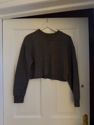 Grå croppad tröja från Zara - Säljer en grå croppad tröja från Zara med ribbade muddar och rund hals. Super mysig knappt änvänd (strlk S).