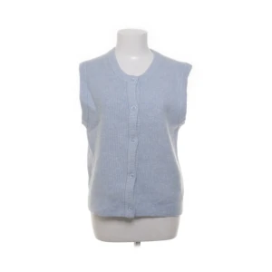 Ljusblå stickad väst från Samsøe Samsøe - Superfin ljusblå stickad väst från Samsøe Samsøe med rund hals och knappar framtill. Västen är blandannat gjord av alpacka och merinoull! Perfekt att styla över  t-shirt eller skjorta för en chill look. 