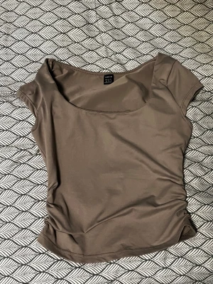 Beige topp med rund hals från SHEIN - Snygg beige topp från SHEIN med rundad halsringning och korta ärmar. Tunn och mjuk i materialet, perfekt för dig som gillar stilrena och enkla plagg. Passformen är normal och tyget har en lätt stretch. Enkel att matcha med jeans eller kjol.