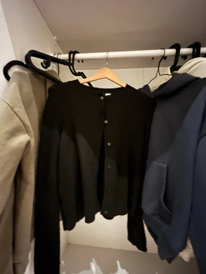 Svart kofta med knappar - Svart, klassisk kofta med knappar framtill. Långärmad och i mjukt stickat material, Använd men funkar toppen😁👍