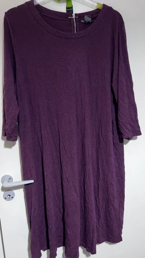 Lila långklänning från Lindex 2XL - En enkel och flowy lila långklänning från Lindex i storlek 2XL. Klänningen har trekvartsärm, rund halsringning och dragkedja bak. Perfekt för dig som gillar en avslappnad och bekväm stil.
