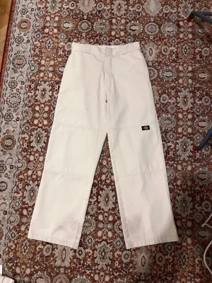 Vita straight byxor från Dickies - Säljer ett par vita Dickies byxor med rak passform och klassisk Dickies-logga på benet. Byxorna har dragkedja framtill, samt fickor både fram och bak. Materialet är slitstark bomull och midjan är normal. 