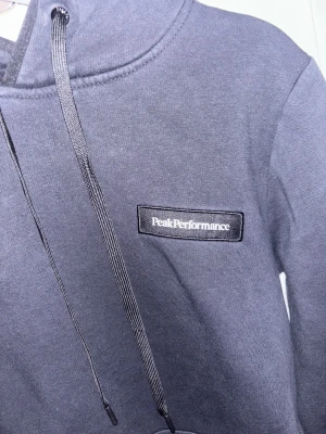Peak performance hoodie stl M - Riktigt snygg hoodie, den är använd ett par gånger. Svart hoodie med vit täxt passar nästan till allt. Bra i storlek jag är 160 och den sitter bra på mig🥰Nypris är 1200kr