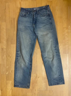 Baggy FSBN jeans - Säljer ett par klassiska blå jeans från FSBN i storlek 27/30. Jeansen har fem fickor, raka ben och normal passform. Tillverkade i 100% bomull med snyggt tvättad look och ljusare partier på låren. Perfekt för dig som gillar enkel och stilren denim.
