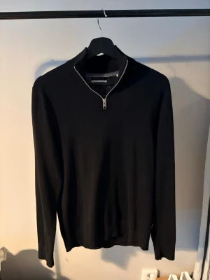 Svart stickad tröja med half zip - Säljer en svart stickad tröja från Jack and Jones med half zip-dragkedja i halsen. Tröjan har lång ärm och en clean, stilren look som passar perfekt till både jeans och chinos. Materialet är mjukt och bekvämt, perfekt för kyligare dagar.