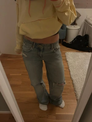 Ljusblå jeans med hål - Jeans med hål från Zara. Storlek 34. De är utsydda i benet så att de passar mer som bootcut/wide istället för rakare passform. De är även uppsydda och passar bra (rätt långa i benen) för mig som är 163 cm. Helt slutsålda i storleken på Zaras hemsida. 