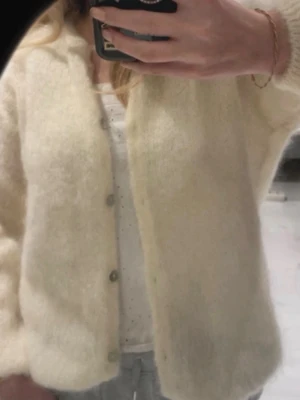 Beige fluffig kofta från Design by SI - Supermjuk och fluffig beige kofta från Design by SI, tillverkad i Italien. Knappar framtill och är gjord i en lyxig mix av kid mohair, nylon och elastan. Köpte den för 800kr kan gå ner i pris vid snabb affär