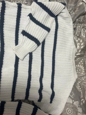 Vit och marinblå stickad randig tröja - Säljer en stickad tröja i vitt med marinblå ränder. Tröjan har lång ärm och är grovstickad med breda muddar vid ärmslut. Perfekt för dig som gillar en klassisk och chill stil.
