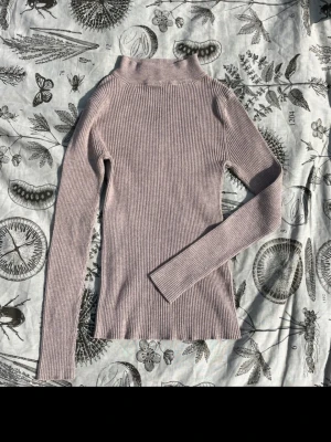 Beige ribbad polotopp från Atmosphere - Säljer en beige ribbad polotopp från Atmosphere i storlek 38. Toppen har lång ärm, hög krage och är i ett mjukt, stretchigt material som sitter snyggt på kroppen. Perfekt att styla med jeans eller kjol för en clean look.