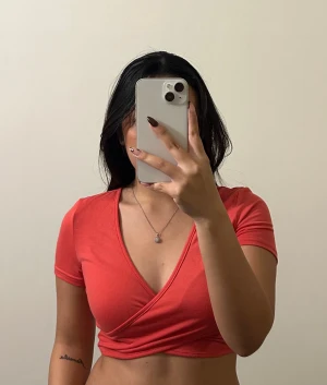 Korall croppad topp från SHEIN - Snygg korall croppad topp från SHEIN med omlott-design och djup v-ringning. Toppen har korta ärmar och är gjord i mjuk och stretchig. Skriv vid frågor 🥰