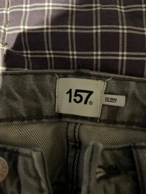 Grå jeans från 157 i storlek XS - Säljer ett par grå jeans från 157 i storlek XS. Klassisk femficksmodell med knappgylf och bälteshällor. Jeansen har en rak passform och är tillverkade i ett slitstarkt bomullsmaterial. Perfekta till sneakers eller boots.