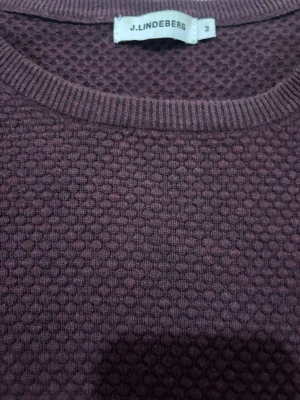 Vinröd stickad tröja från J.Lindeberg - Säljer en vinröd stickad tröja från J.Lindeberg i storlek M. Tröjan har ett diskret strukturmönster över hela ytan, rund halsringning och långa ärmar. Perfekt för dig som vill ha en stilren men ändå unik look. Hade passar bra om du är 160-170cm o väger 60-66 typ