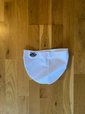 Vit mössa med svart brodyr - Säljer en vit mössa med svart broderad logga framtill. Mössan är mjuk och stretchig med enkel design och passar perfekt för dig som gillar streetwear. Materialet känns som bomull eller bomullsblandning. Snygg och clean look! Helt ny