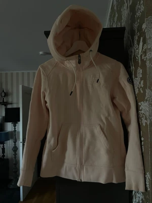 Ziphoodie från Pelle P - En ljusrosa ziphoodie från Pelle P. Broderad logga på vänster bröst. På vänster arm finns en ficka o ytterligare en logga. Storlek S
