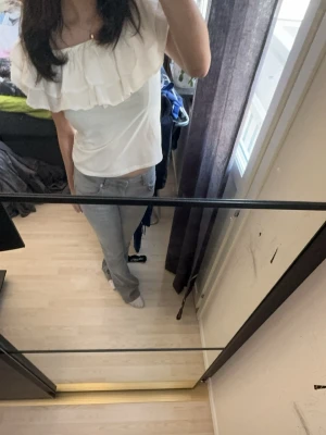 Vit volangblus med offshoulder - Snygg vit blus med volangdetaljer och offshoulder-design. Perfekt för dig som vill ha en trendig och luftig topp med romantisk känsla. Passar till både jeans och kjol för en cool look.
