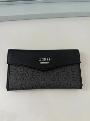 Plånbok från Guess - Snygg svart plånbok från Guess med silverfärgad logga framtill. Den används inte🫶🏼