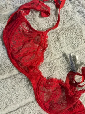 Röd spets-bh med bygel - Snygg röd bh i transparent spets med bygel och tunna axelband.  För liten för mig (Har 70D). 