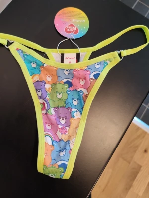 ROMWE x CAREBEARS Thong - ROMWE x CAREBEARS stringtrosa i limegrönt. Mjuka och stretchiga. Fina hjärtsnycken vid banden på varje sida. Storlek S. Helt nya med lapp kvar!
