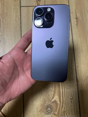 Lila iPhone 14 Pro med dubbla kameror - Snygg lila iPhone 14 Pro med stilren design och två stora kameror på baksidan. Mobilen har en matt glasbaksida och ram i metall. Apple-loggan syns tydligt på baksidan. Perfekt för dig som gillar modern teknik och vill ha en riktigt fräsch lur.