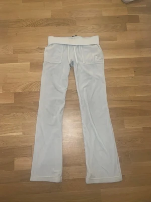 Vita Juicy Couture mjukisbyxor - Supermjuka och sköna vita mjukisbyxor från Juicy Couture med utsvängda ben, har en fläck på benet , det går nog bort i tvättmaskinen, ena snörernas silver sak har gott av som man ser på sista bilden. Storlek xs men passar någon som är 165-171 cm lång original pris 1200kr