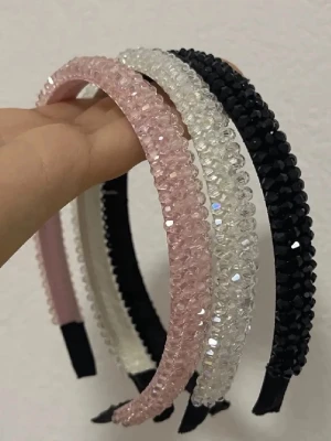 Diadem med pärlor i rosa, vitt och svart - Tre snygga diadem med glittrande pärlor i rosa, vitt och svart. Diademen har en klassisk form och är täckta av små fasetterade pärlor som ger en lyxig känsla. Perfekta för att lyfta din look med lite extra bling. Materialet är plast och textil.