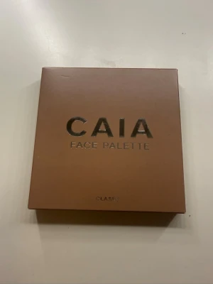 CAIA Face Palette Classy - Snygg ansiktspalett från CAIA i färgen Classy. Kommer i en stilren, fyrkantig brun förpackning med metallictext. Perfekt för att skapa en fräsch bas med contour, highlight och rouge. Smidig att ha med i väskan och enkel att använda till vardagslooken. Kan diskutera pris