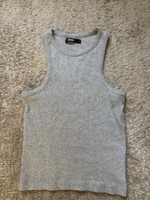 Ljusgrå ribbad linnetopp Bik Bok - Säljer en ljusgrå ribbad linnetopp från Bik Bok. Toppen är ärmlös och har en slim passform. Perfekt att styla till jeans eller kjol! Vid frågor är det bara att höra av sig!