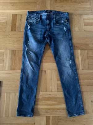 Replay jeans - Säljer ett par blå slim jeans med slitningar och distressed detaljer på både fram- och baksida. Jeansen har klassisk femficksmodell och normal midja. Perfekta för en avslappnad och trendig look.👌⭐️ Pris ej hugget i sten!