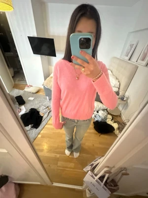 Rosa stickad tröja i mjukt material - Säljer en söt rosa stickad tröja med rund halsringning och långa ärmar. Tröjan har ribbstickade muddar vid ärmslut och nederkant. Perfekt för att addera färg till din garderob och passar till både jeans och kjol.