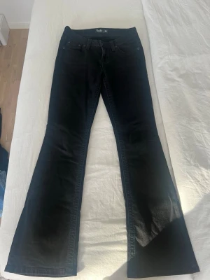 Svarta bootcut jeans - Säljer ett par svarta bootcut jeans. Jeansen har snygga detaljer på bakfickorna med mönstrad design och klassisk femficksmodell. Materialet är stretchigt denim som sitter bekvämt och ger en schysst siluett. Inköpspris: 2500kr