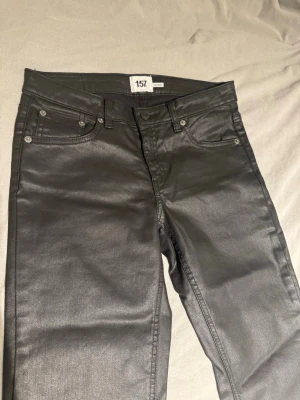 Svarta coated jeans från 157 - Säljer ett par svarta skinnbyxor från Lager 157. Jag köpte fel storlek och insåg inte det förens jag kom hem och tog bort pappret som gjorde att jag inte kunde byta den.