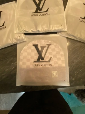 Louis Vuitton rutmönstrad mössa - Snygg mössa från Louis Vuitton i beige och brunt rutmönster. Mössan har en vikt kant med en liten patch där det står Louis Vuitton Paris. Perfekt accessoar för dig som gillar exklusiv och trendig stil.