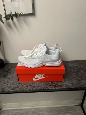 Nike Air Presto vita sneakers - Fräscha vita Nike Air Presto sneakers med mesh-överdel och plastdetaljer vid snörningen. Skorna har en sportig siluett, rund tå och tjock sula för extra komfort. Perfekta för dig som gillar stilrena och lätta sneakers.