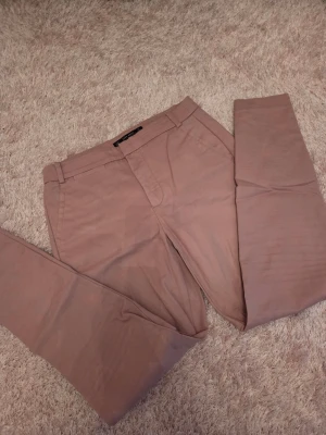 Beiga chinos från Jack & Jones - Snygga beiga chinos från Jack & Jones med klassisk rak passform. Byxorna har bälteshällor, två sidofickor fram och en bakficka med knapp. Tillverkade i mjukt bomullstyg som ger en skön känsla och stilren look.