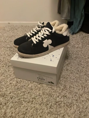 The Gallerist Moritz vinter sneakers - Mörkblå sneakers från The Gallerist, modell Moritz, med vit sula och vit detalj på sidan. Skorna har snörning och är fodrade med mjuk fårskinn för extra värme. Tillverkade i Portugal. Perfekta för kalla dagar.