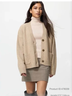 Beige kofta från Uniqlo i ullmix - Mysig beige kofta från Uniqlo i storlek S. Koftan är stickad i ullblandning, har två stora fickor framtill och stängs med tre knappar. Perfekt för lager-på-lager och har en avslappnad, loose passform med ribbade muddar. Sitter som en xs